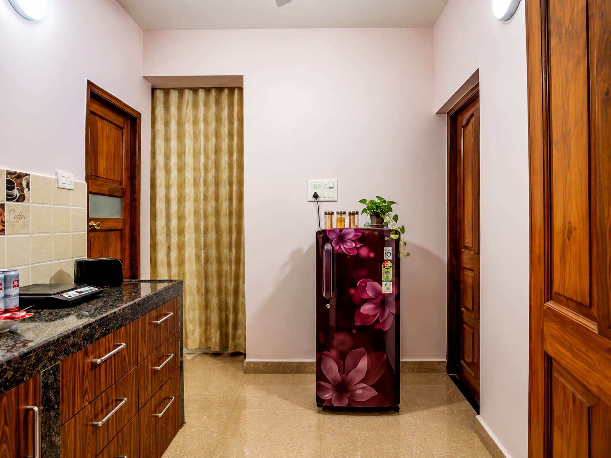 A studio pantry at Misquita Comforts with a granite counter, wood cabinets and a refrigerator.