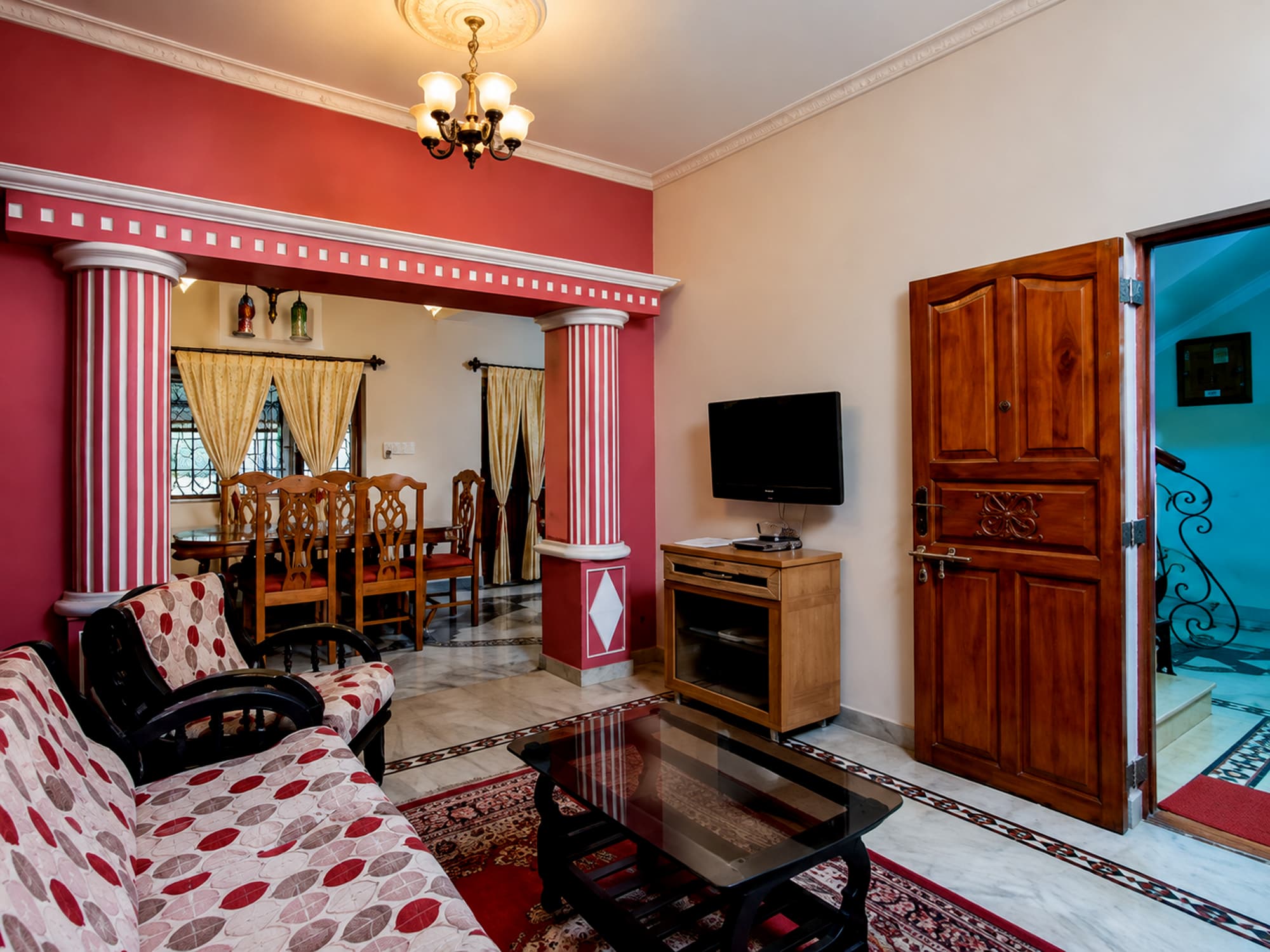 The sitting and dining room at Misquita Exclusive, with carved wooden furniture and a columned archway.
